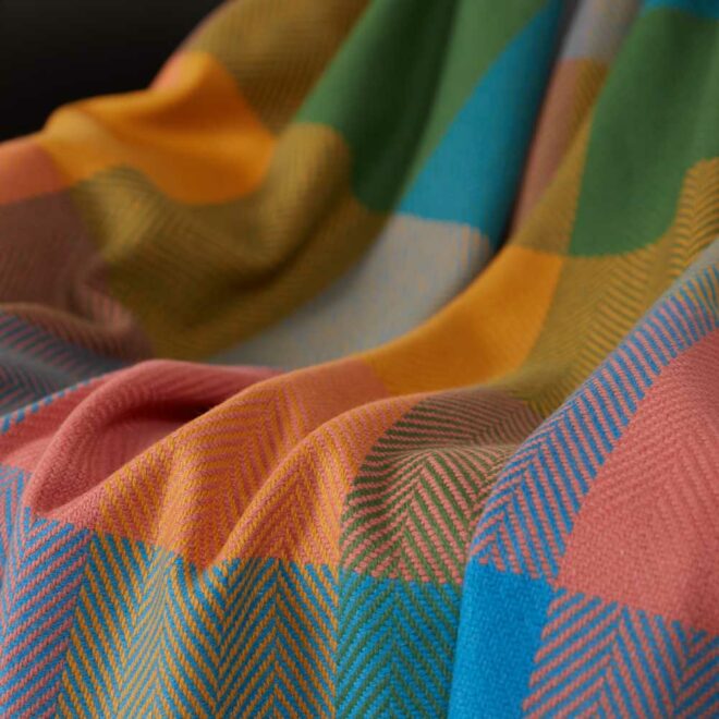 A brightly coloured large check throw folded over a chair